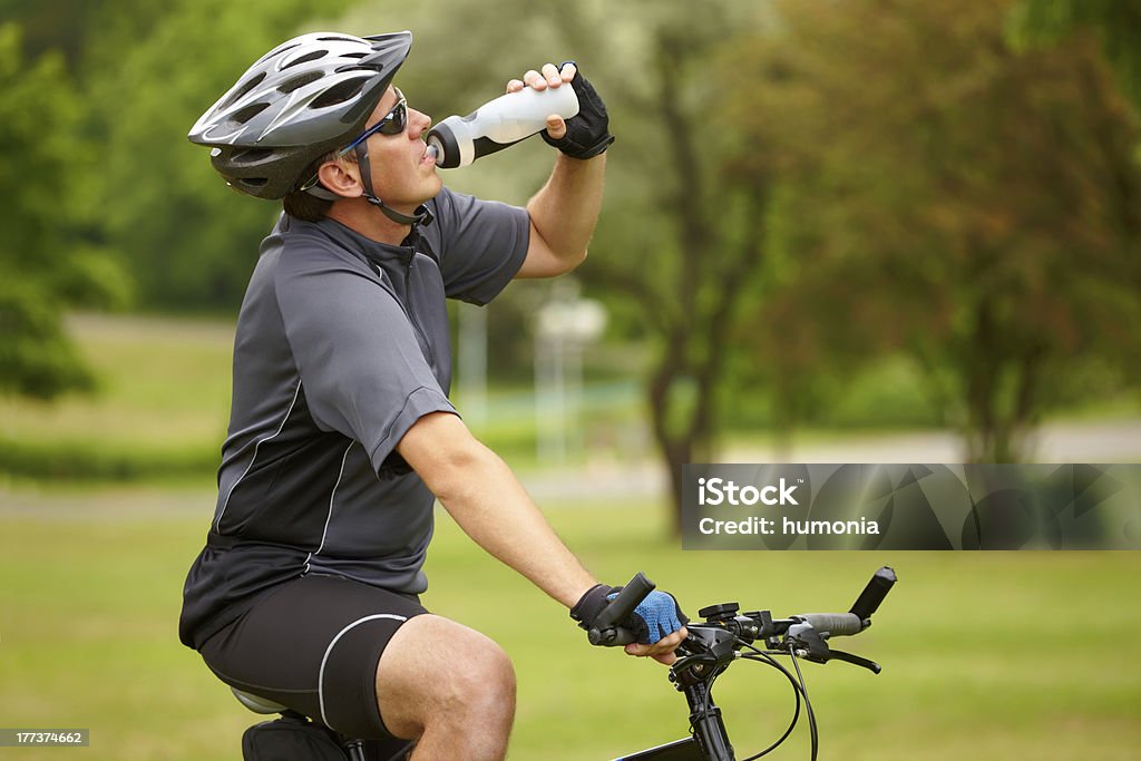 Motociclista con botella de agua - Foto de stock de Andar en bicicleta libre de derechos