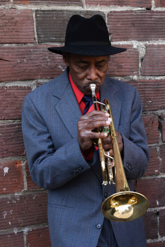 African American man playing an old trumpet in a gritty alley.