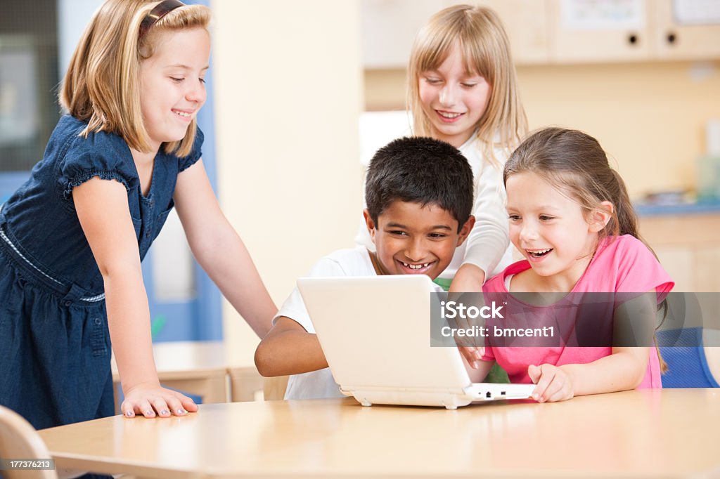 Escola primária em crianças a fazer trabalho de equipa no computador portátil na sala de aula Moderna - Royalty-free 6-7 Anos Foto de stock