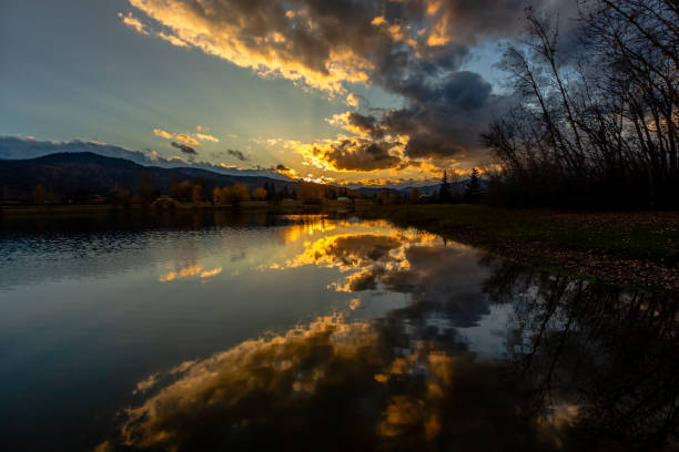 Dramatic sky reflection in the calm pond water in the park in fall season