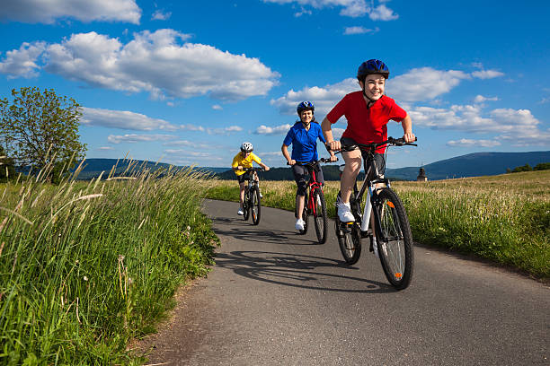Three people biking on a paved path surround by tall grass