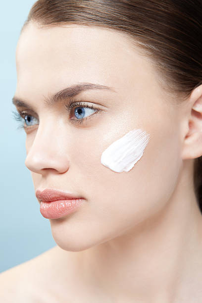 Beautiful woman apply moisturizer cosmetic cream on face stock photo