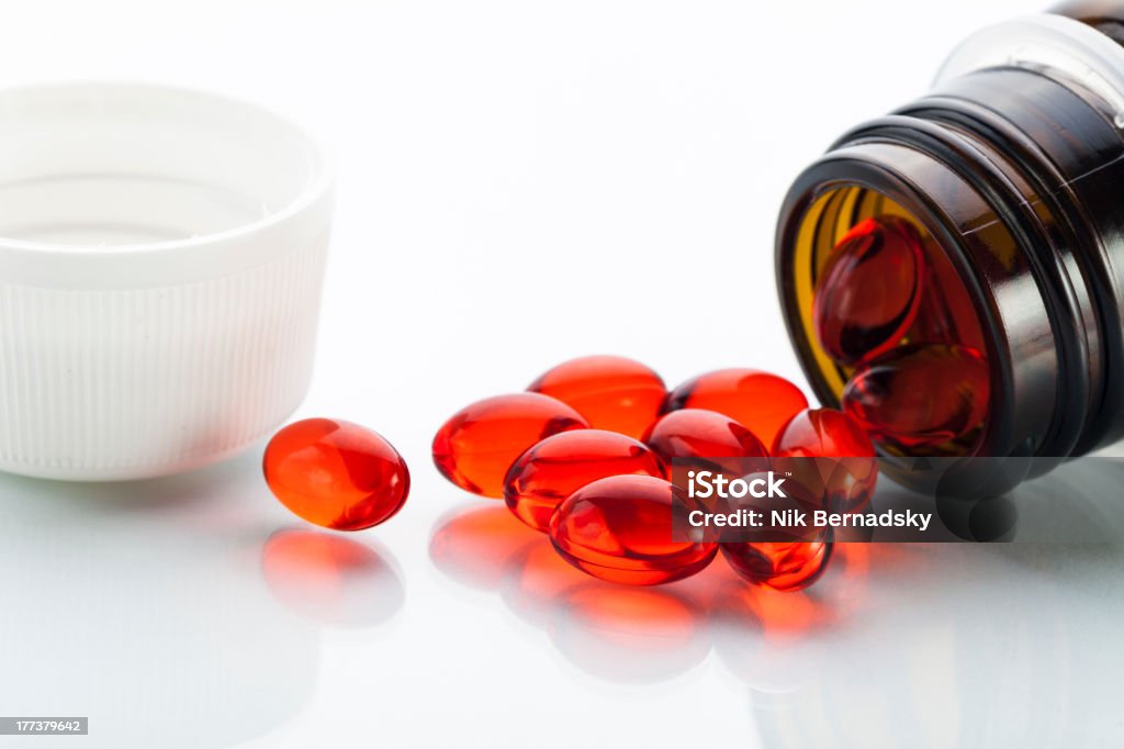 Vitamin E capsules Transparent red capsules with vitamin E poured out of glass bottle Acetate Stock Photo