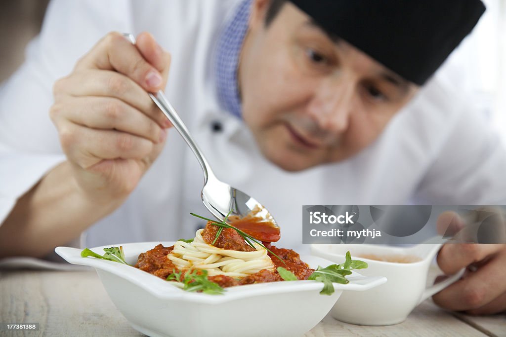 Male chef in restaurant Male chef in restaurant kitchen is garnishing and preparing pasta dish Chef Stock Photo