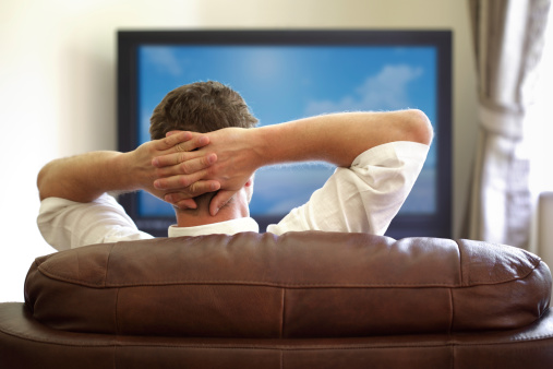 Man sitting on a sofa watching tv with hands folded behind his headPlease see similar picture from my portfolio: