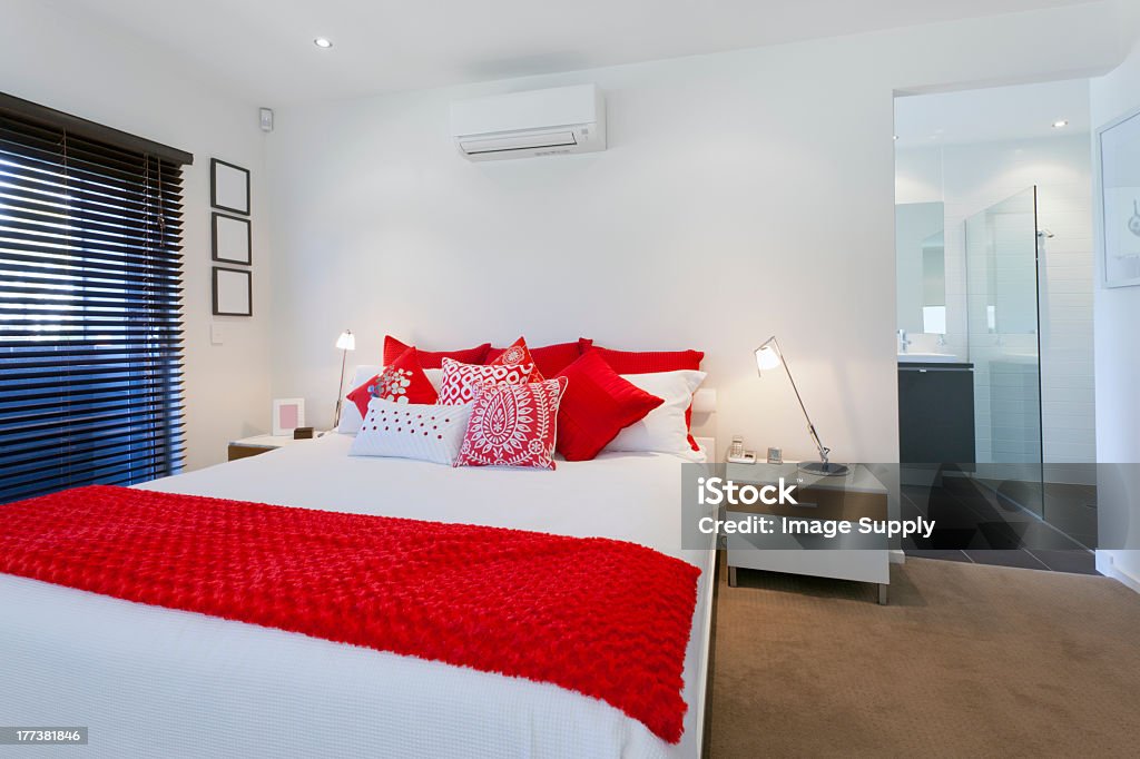 Master bedroom decorated in white with red accents Stylish master bedroom and bathroom in luxury Australian mansion Australia Stock Photo