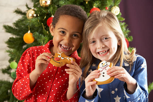 Two Young Children Eating Christmas Treats stock photo