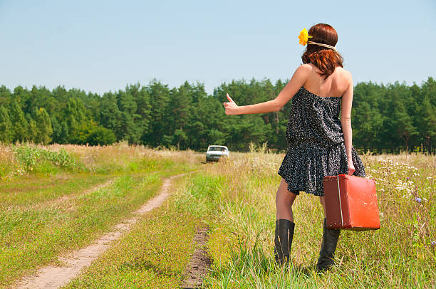 Beautiful brunette with a suitcase in the countryside. Photos in the old style.