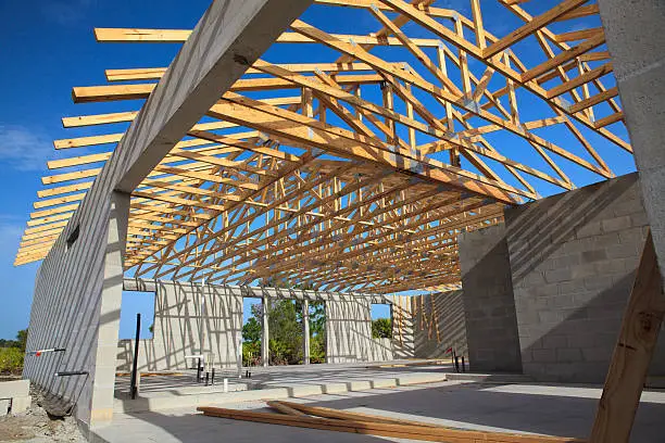 Cement block walls with wooden roof truss. Roof open with blue sky.