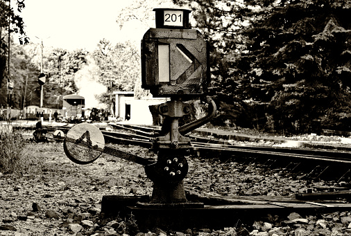 old vintage manual railway or rail switch. steel bar arm and metal weigh. closeup view. antique track crossing device and mechanism. retro style concept. closeup view. blurred rail yard background