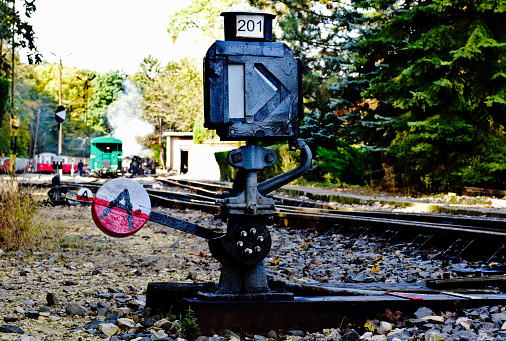 old vintage manual railway or rail switch. steel bar arm and metal weigh. closeup view. antique track crossing device and mechanism. retro style concept. closeup view. blurred rail yard background