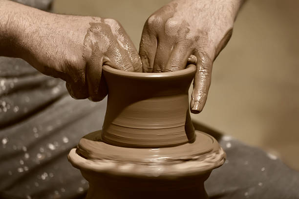 istock Potter makes a clay pot on spinning wheel in workshop 177384190