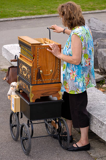 Barrel organist A woman barrel organ player, complete with monkey, playing her music to an empty street. hurdy gurdy stock pictures, royalty-free photos & images