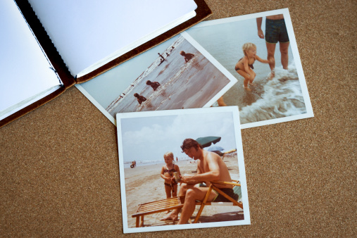 Old photo album and photographs from the early 1970's of family at a beach on a bulletin board.
