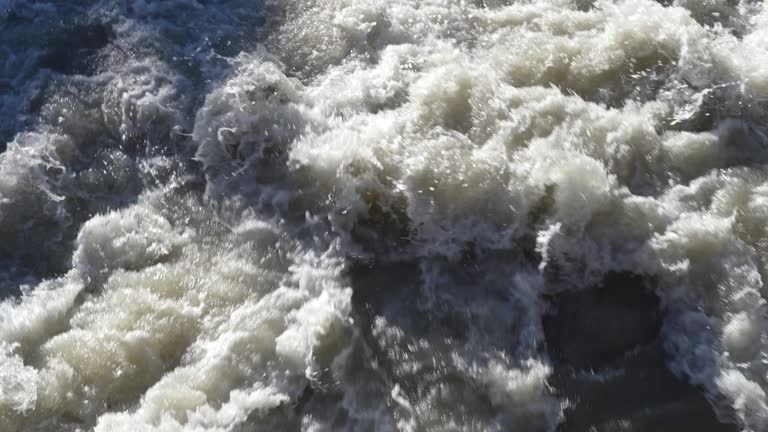 Up and down drone aerial view of the a river swollen after heavy rains. The water flows quickly. Risk of flooding and overflow. General contest of a river flood