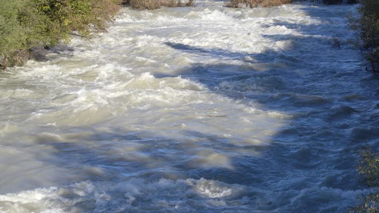 The Serio river swollen after heavy rainfall and floodwater crashing through valley. The water flows fast from the high valley to the plain. River in Province of Bergamo, northern Italy