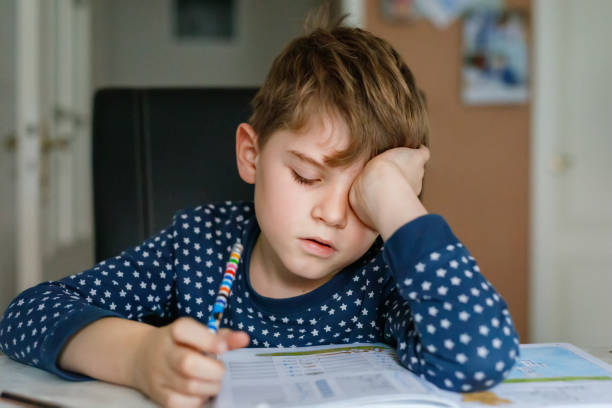 istock Hard-working sad school kid boy making homework. Upset tired child on home schooling, learning. 1773850674