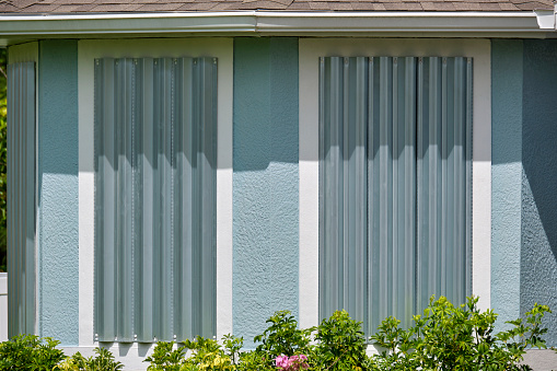 Steel sheets mounted as storm shutters for hurricane protection of house windows. Protective measures before natural disaster in Florida.