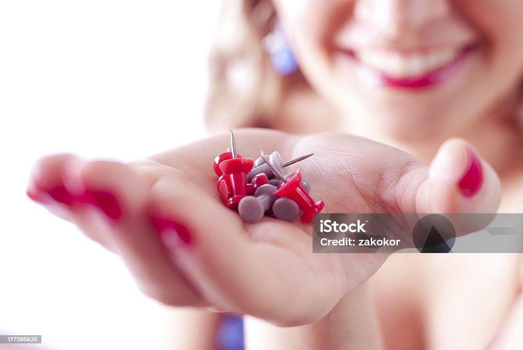 Donna sorridente con la mano che tiene pushpins, thumbtacks - Foto stock royalty-free di Adulto