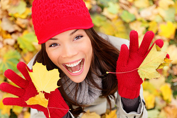 Happy autumn xwoman playing with leaves. Fall xwoman smiling - Autumn portrait of happy lovely and beautiful mixed race Asian Caucasian young xwoman in forest in fall colors.