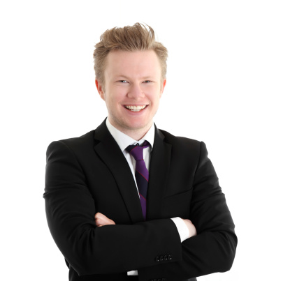 Young happy businessman. Wearing a black suit with a purple tie. White background.