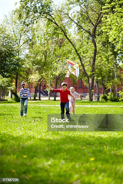 Children Running And Flying A Kite Stock Photo - Download Image Now - Child, Playful, Public Park