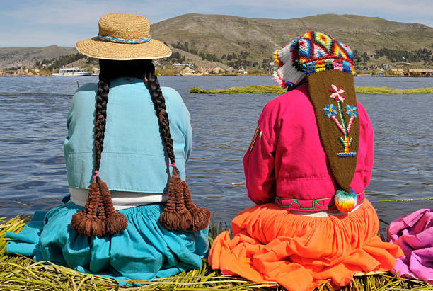 View of two traditionally dressed young Uros Indian girls looking at the lake Titicaca.