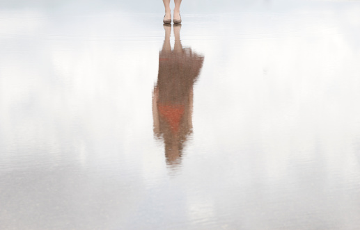 Female body appears in the reflection of the water.