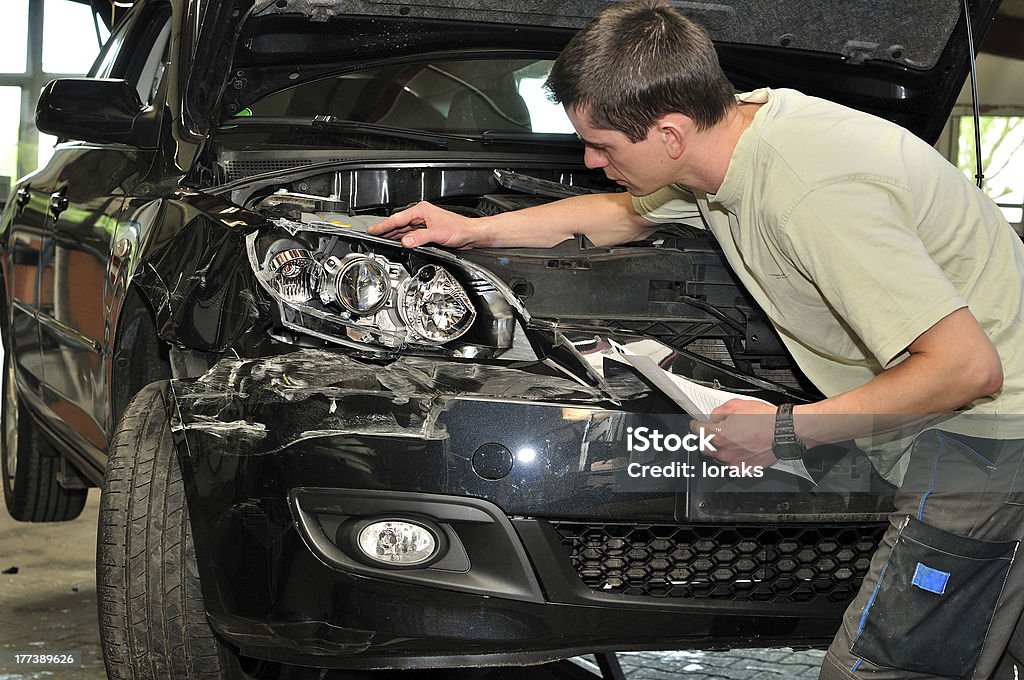 Car damage examining. An insurance inspector examining a black car after a crash. Car Stock Photo