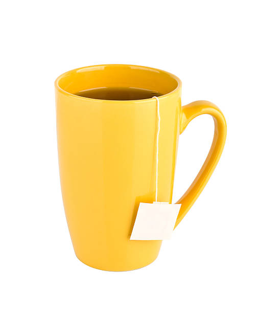 Yellow mug of tea isolated on white background "Cup of tea with tea bag (blank label) inside, isolated on white background" glass cup of boiling water stock pictures, royalty-free photos & images