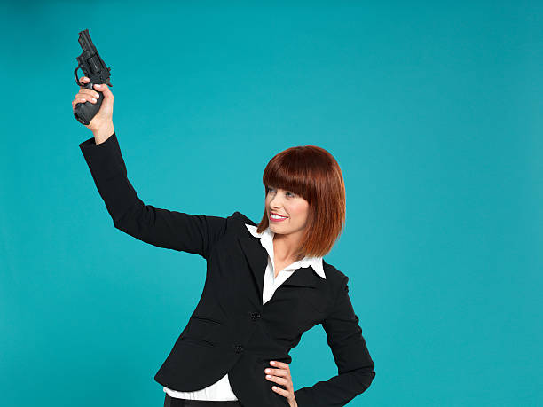 atraente, jovem mulher de negócios, apontando para arma no ar - handgun gun blue black imagens e fotografias de stock