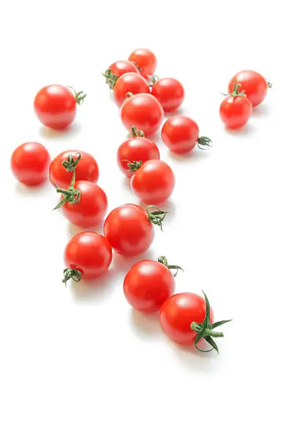 Fresh ripe cherry tomatoes scattered isolated on white background.