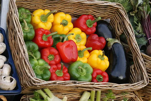 Sweet peppers and aubergines in a basket on a greengrocers stall in Norfolk UK