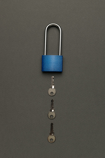 A closed lock with three keys on a gray background. The concept of protection.