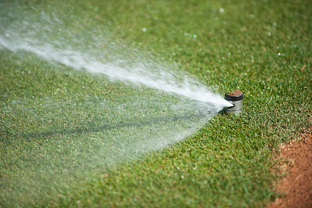 A working lawn sprinkler watering a baseball field.