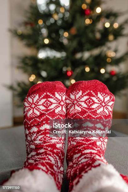 Partial View Of Feet In Colorful Wool Socks Against Christmas Tree Background Stock Photo - Download Image Now