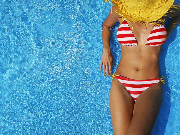 Woman sunbathing in a striped bikini and straw hat stock photo