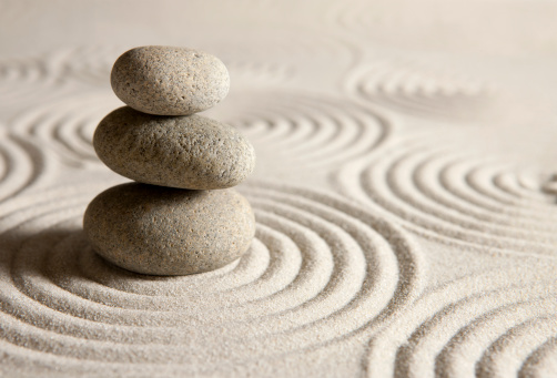 Stack of three stones on sand background