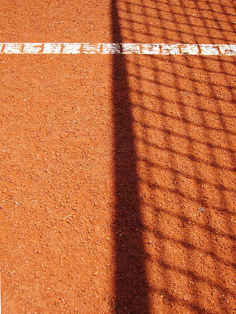 Female tennis player in sportswear hitting ball with racquet on clay court during match.