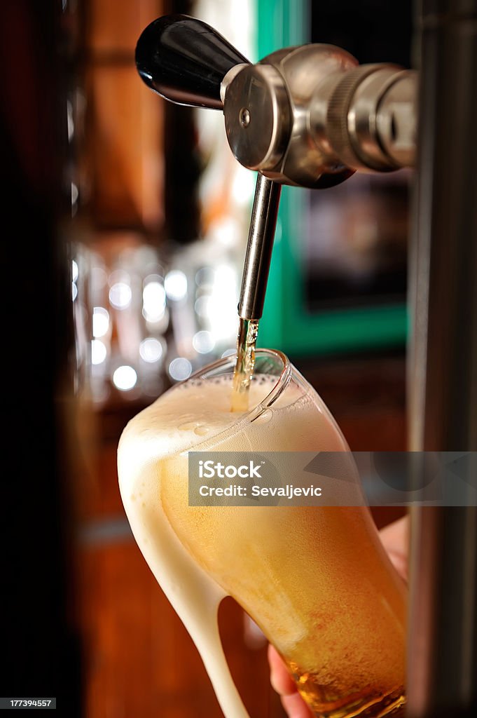 Filling glass with beer Glass overflow of delicious beer foam Beer - Alcohol Stock Photo