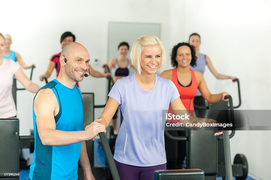 Academia de ginástica com instrutor líder pessoas de exercícios - Foto de stock de Academia de ginástica royalty-free