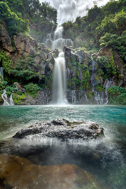 Waterfall Moving water at the beautiful Trois Bassins waterfall as it plunges into a blue lagoon on Reunion Island. réunion stock pictures, royalty-free photos & images