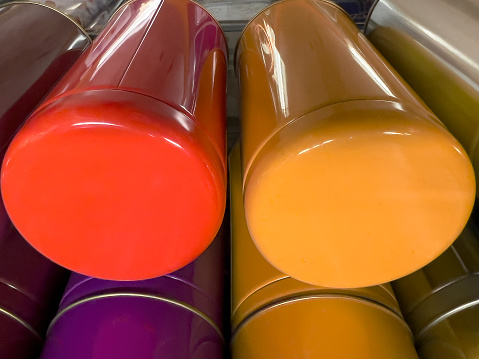 Metal tea caddies in cheerful colors for storing looseleaf tea displayed in a tea shop.