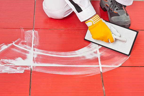 trabajador con pala de aplicar mezcla de caucho azulejos - tiled floor tile floor grout fotografías e imágenes de stock