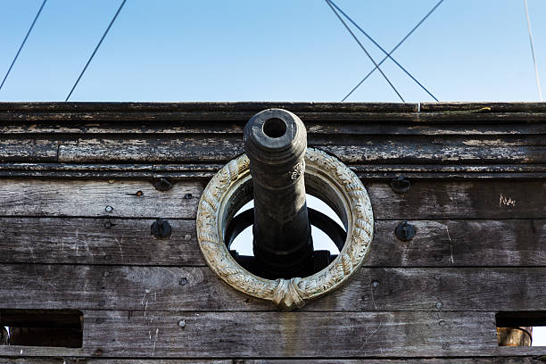 The mouth of a cannon out of the hatch of a pirate ship.