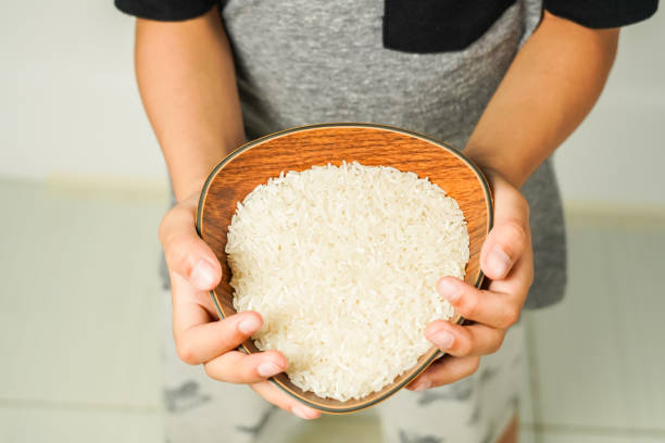istock rice in a wooden bowl held by hand, zakat concept 1774001900