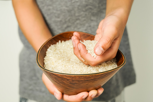 rice in a wooden bowl held by hand, zakat concept