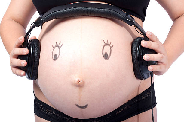 Kopfhörer auf den schwangeren Bauch mit smiley-Gesicht – Foto