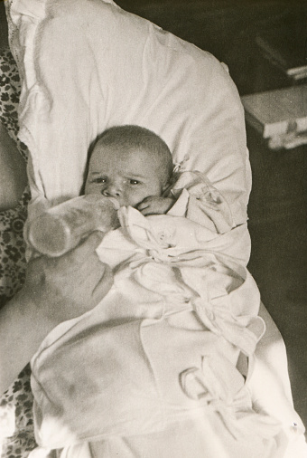 Vintage photo of a mother bottle-feeding her baby daughter. Visible noise.See my other family photos here: