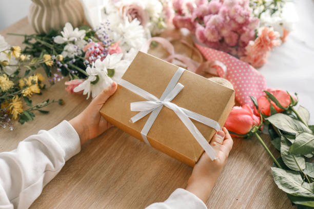 istock Gift box in hands with flowers at home 1774033578